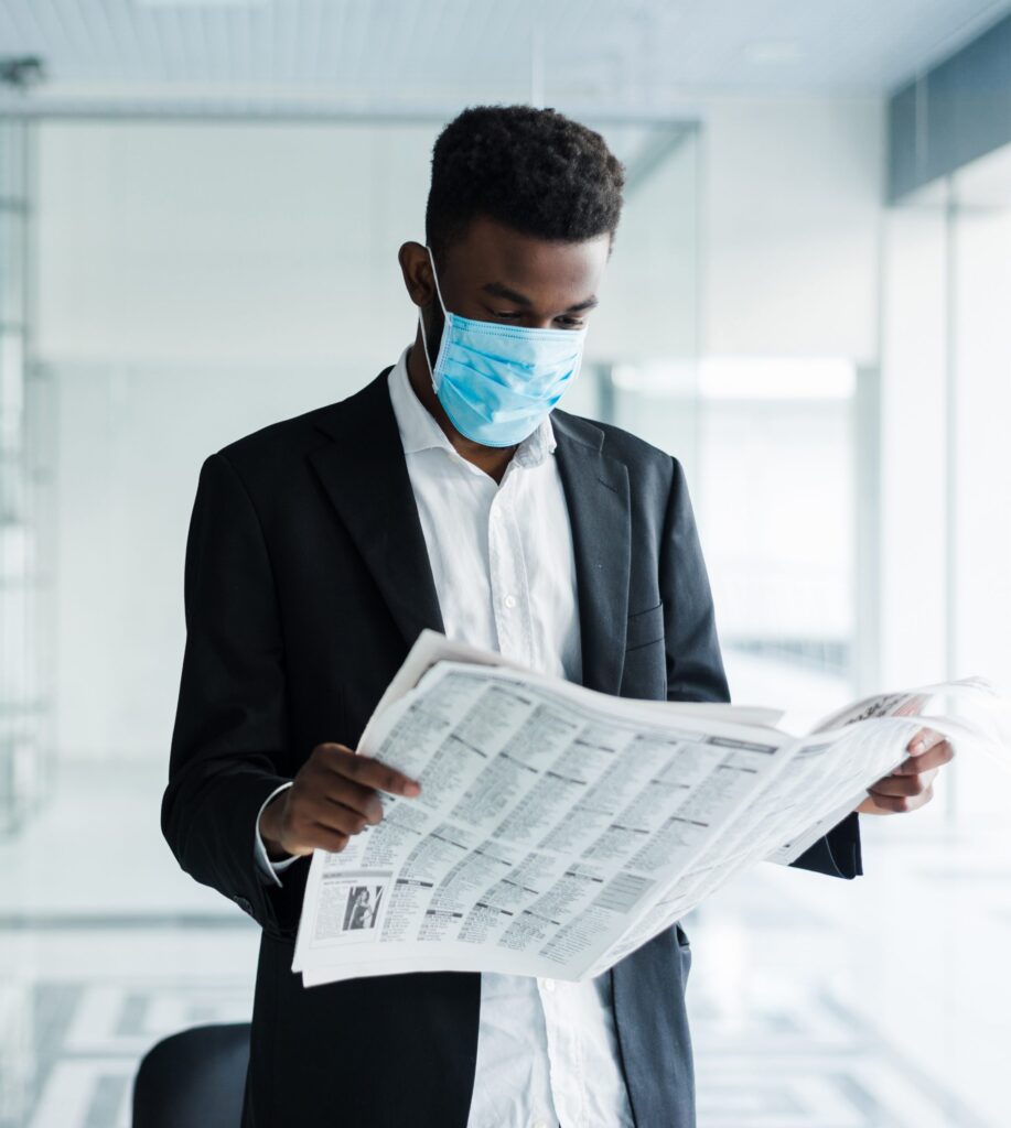African business man in mask reading the newspaper at office building