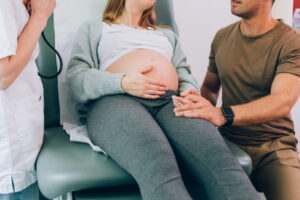 Pregnant woman with partner at prenatal doctor visit.